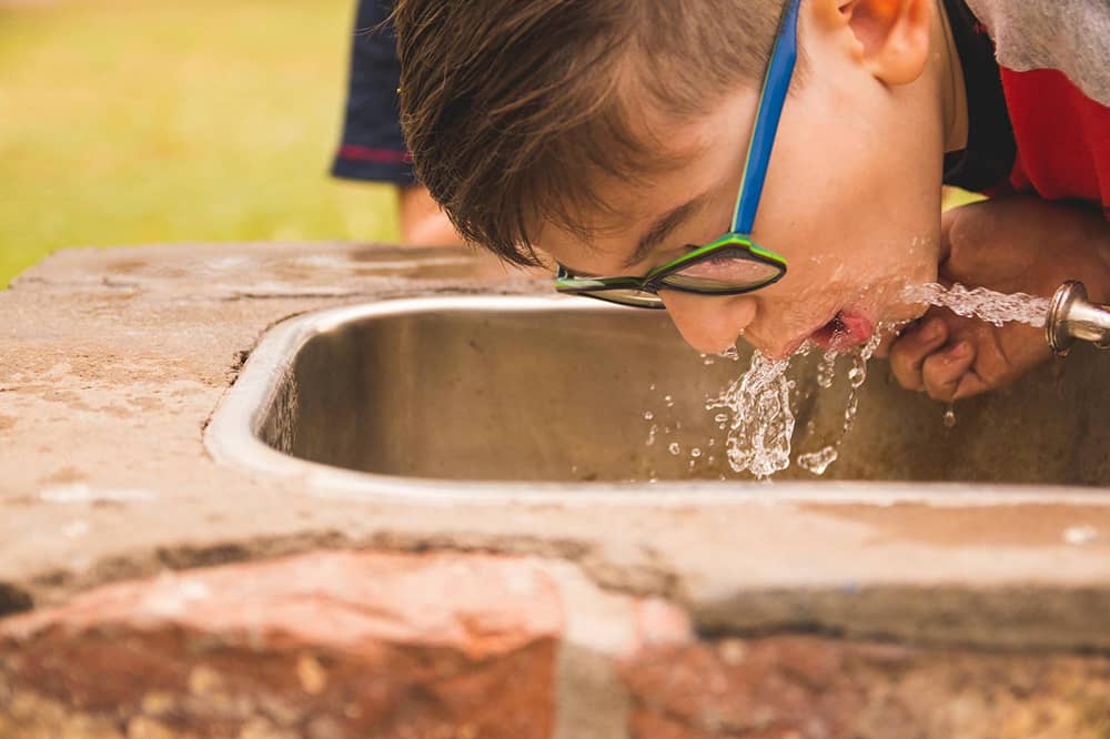 Park visitor enjoying clean drinking water from fountain treated by Sublime Environmental systems for public health and safety