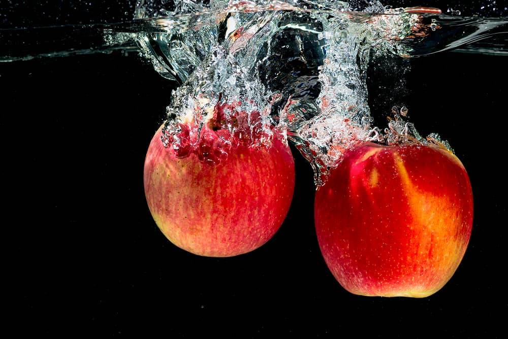 Fresh red apples splashing in pure water treated by Sublime Environmental ozone technology for premium cider production process