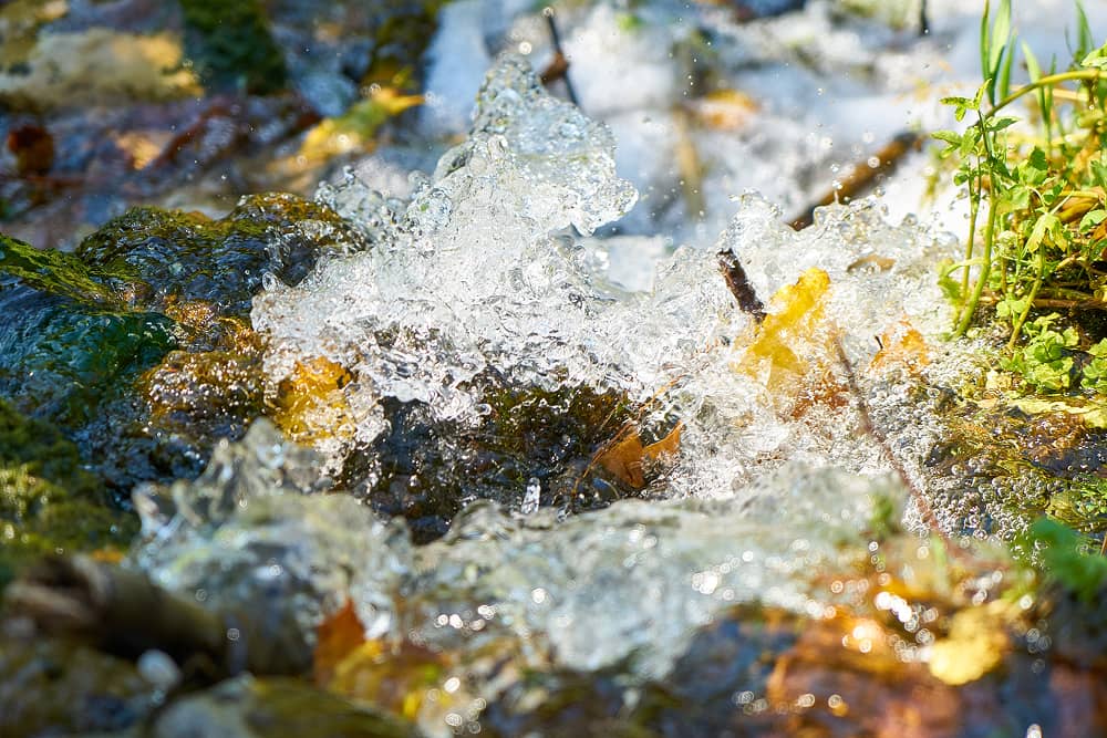 Ice formations on moss-covered rocks representing natural water sources treated by Sublime Environmental mining solutions for environmental protection