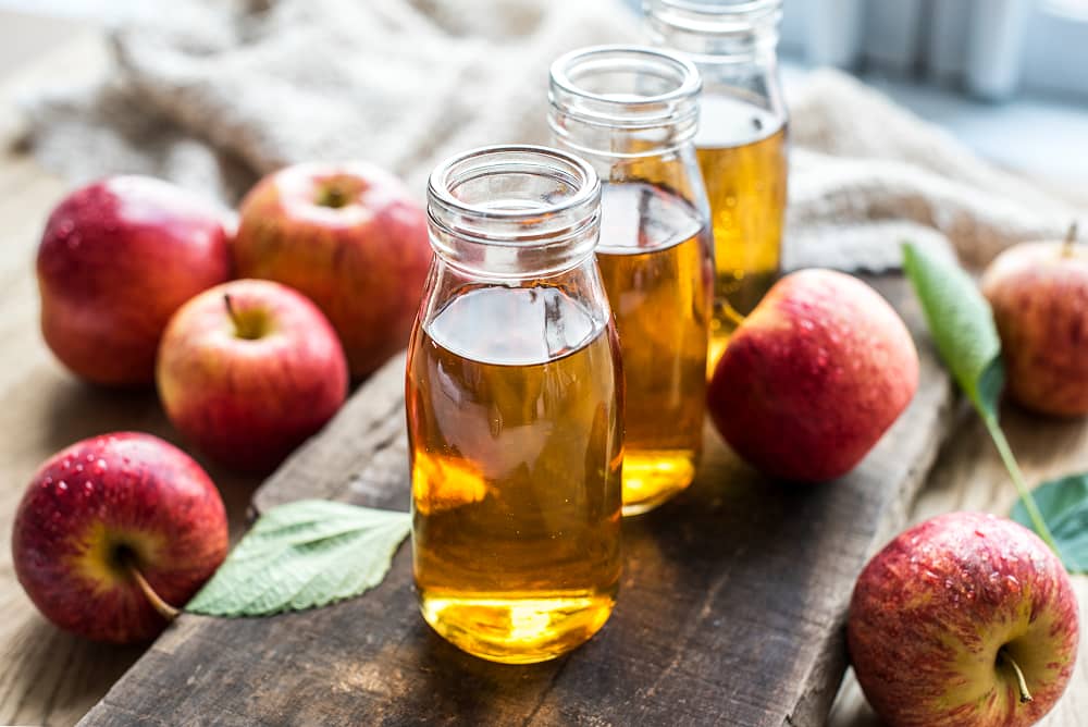 Fresh red apples with bottles of cider showcasing premium water quality for craft beverage production