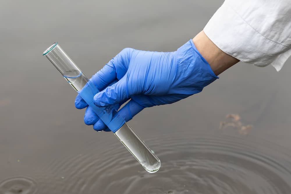 Research scientist collecting water samples for analysis in university fisheries research facility using Sublime Environmental treatment system for precise water parameters