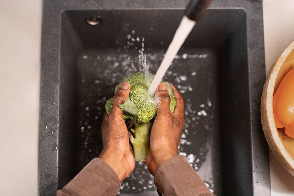 Top view of hands washing produce with Sublime Environmental ozone-treated water for safe food preparation and enhanced flavour